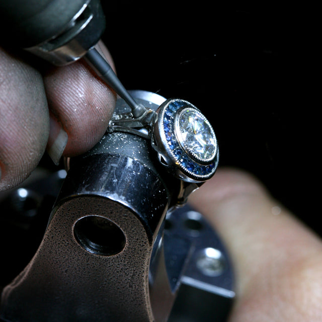 A making of image of a bespoke engagement ring with a diamond in the centre and blue sapphires around it.
